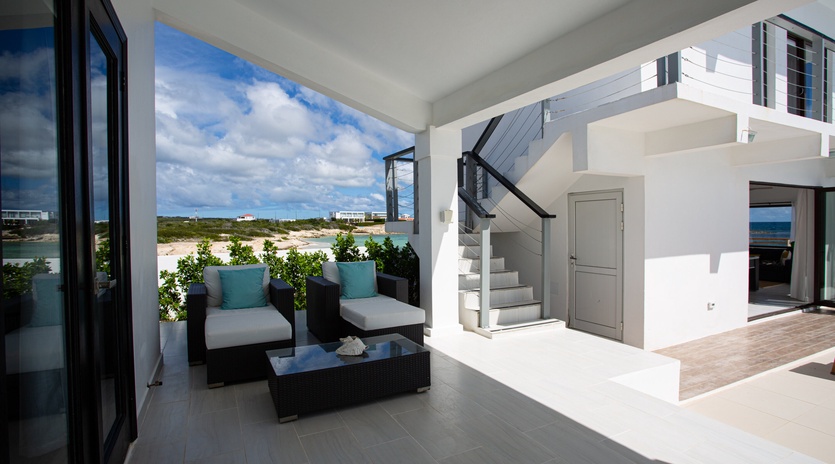 Your private terrace opens to coastal beauty, with plush seating overlooking sandy shores and turquoise waters—a serene spot to savor morning coffee or sunset moments.