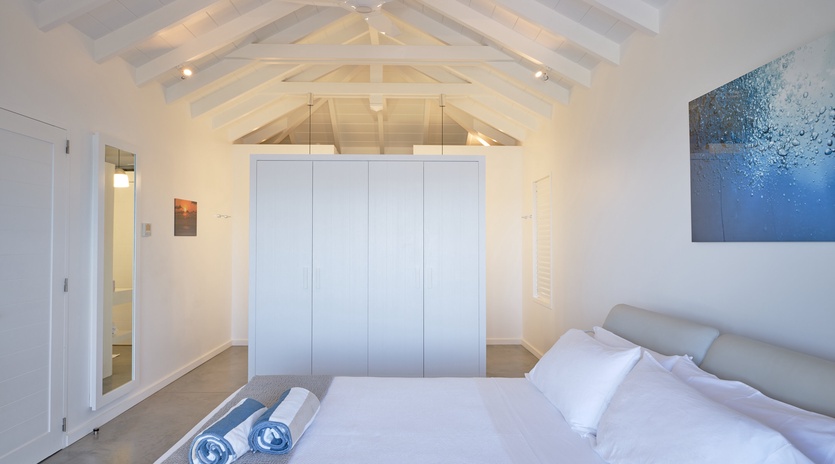 Rest beneath stunning exposed beams in your serene bedroom, where crisp linens and thoughtful artwork create the perfect retreat.