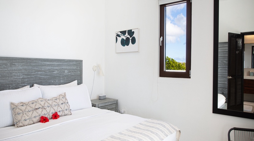 Wake up refreshed in your serene bedroom, where crisp linens and coastal views through the window invite restful mornings and peaceful tropical breezes.