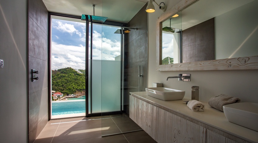 Luxurious bathroom with stunning ocean views where you can shower while gazing at turquoise waters and lush tropical hills.
