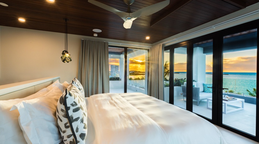 Wake up to golden sunsets and turquoise waters just beyond your door. This elegant bedroom opens onto a private terrace where the ocean stretches endlessly before you—pure coastal luxury.