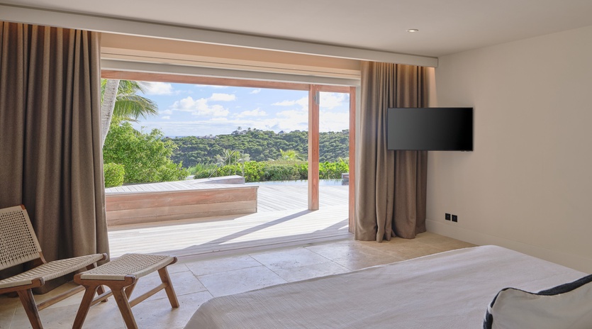 Wake up to stunning tropical views from your private bedroom, where glass doors open to a peaceful terrace overlooking lush greenery.