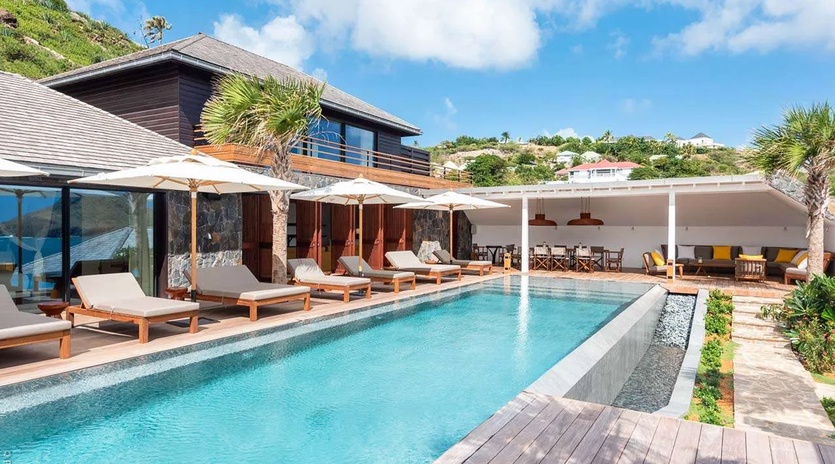 Stunning hillside villa featuring a pristine infinity pool, spacious sun deck with loungers, and covered dining pavilion—an ideal tropical retreat for relaxation and entertaining.