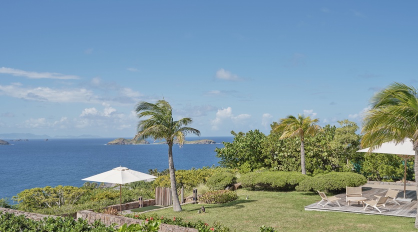 Tropical paradise awaits with manicured gardens, swaying palms, and pristine ocean views stretching to distant islands.