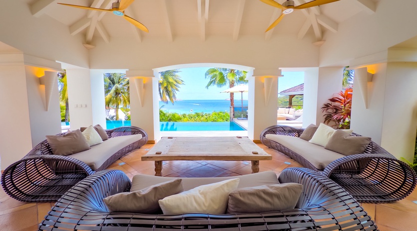 Unwind in your light-filled living space where curved lounges frame stunning views of the pool and ocean beyond. High vaulted ceilings, tropical breezes, and stylish touches create your perfect island escape.