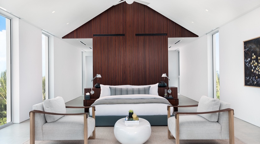 Unwind in your serene sanctuary with floor-to-ceiling windows, contemporary furnishings, and a striking wood accent wall creating the perfect retreat.