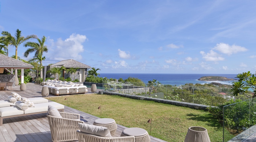 Luxury villa with stunning ocean views, private lawn, and elegant outdoor seating overlooking turquoise waters.