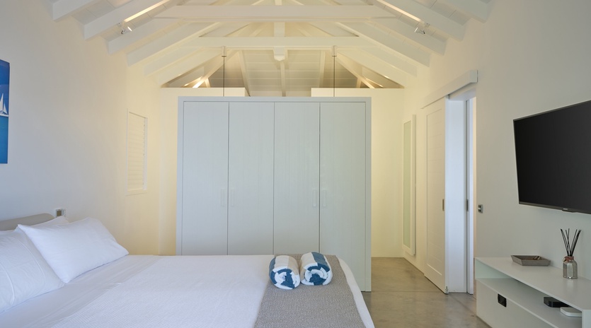 Your serene bedroom sanctuary features exposed wooden beams and crisp white linens under dramatic vaulted ceilings.