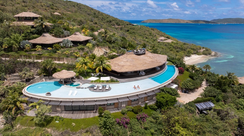Stunning oceanfront villa with curved infinity pool overlooking turquoise Caribbean waters and pristine beaches.