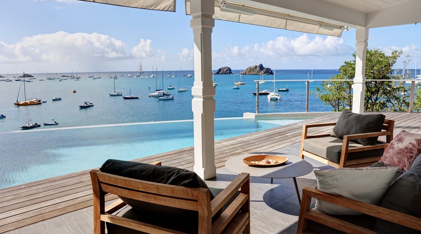 Elegant waterfront terrace with infinity pool overlooking pristine harbor and distant islands.