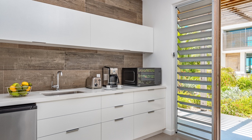 Your sleek kitchen features modern appliances and opens to tropical views through stylish louver doors.