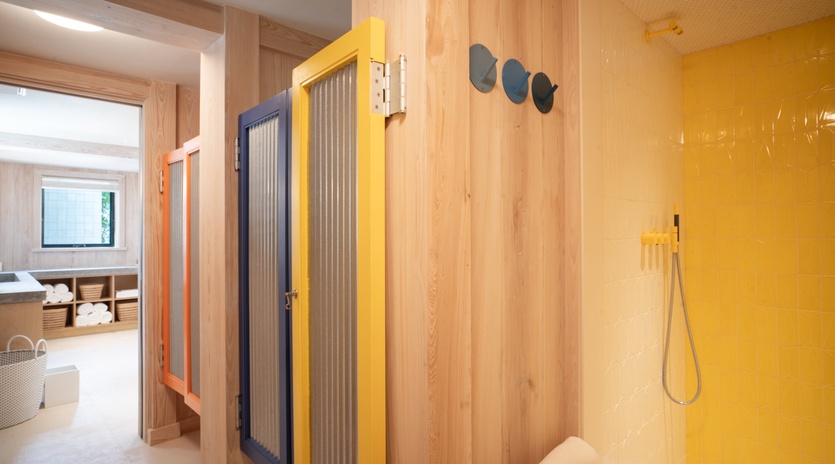 Unwind in your private wellness sanctuary featuring a vibrant yellow shower and rejuvenating sauna with natural wood finishes.