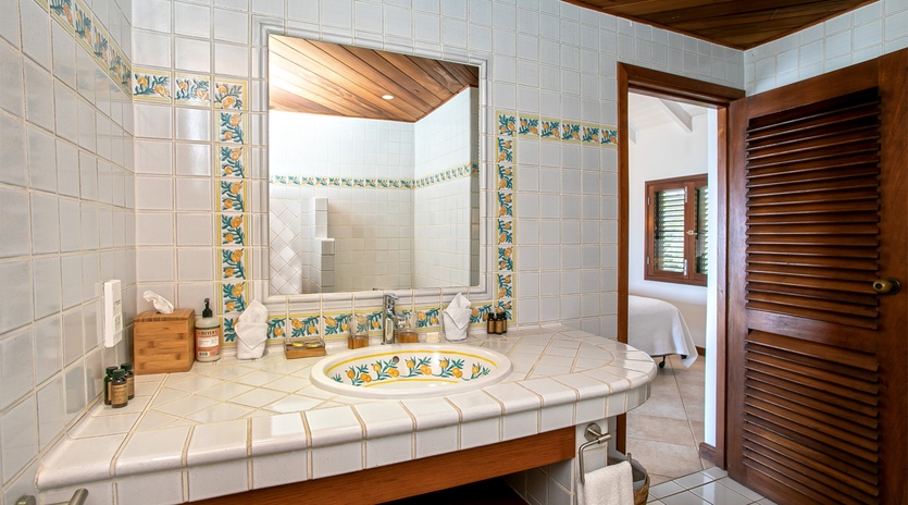 Unwind in your private bathroom featuring handcrafted tile work, warm wood accents, and a colorful hand-painted sink that adds Mediterranean charm to your daily routine.