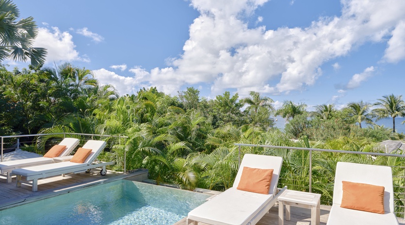 Your private pool terrace offers tranquil lounging with tropical views and orange-accented chairs for ultimate relaxation.