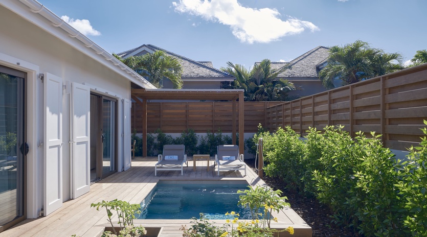 Step onto your private terrace where crystal-clear pool waters invite relaxation amid lush tropical landscaping and comfortable loungers.