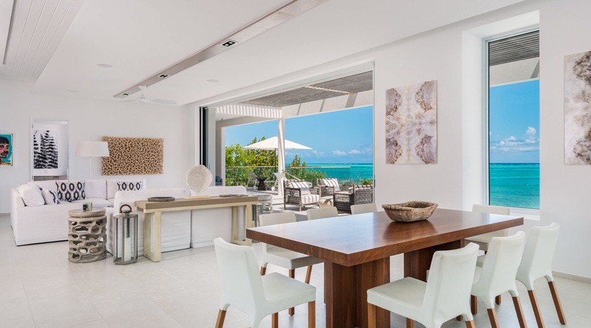 Your elegant dining space opens to breathtaking ocean views, where modern design meets tropical paradise through floor-to-ceiling windows.