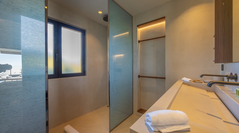 Step into your sleek bathroom sanctuary with a spacious walk-in shower and plush towels awaiting your arrival.