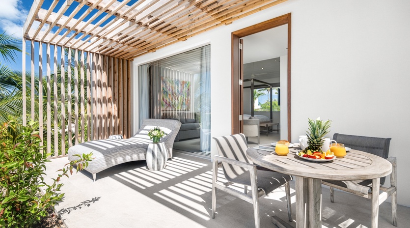 Your private terrace awaits with comfortable lounging and outdoor dining under beautiful latticed shade, perfect for tropical breakfast moments.