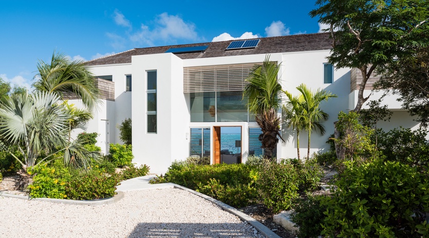 Modern beachfront villa with solar panels and tropical landscaping creates an eco-friendly paradise retreat.