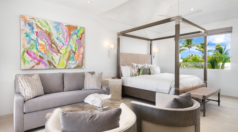 Unwind in your elegant bedroom with tropical views, plush canopy bed, and cozy seating area perfect for morning coffee.