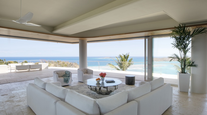 Stunning oceanfront living room with panoramic sea views through floor-to-ceiling windows, perfect for your tropical escape.