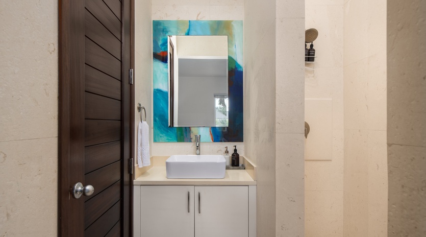 Refresh yourself in this sleek modern bathroom featuring a stylish vessel sink, vibrant artwork, and pristine marble surfaces.