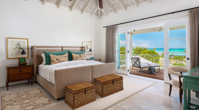 Wake to breathtaking turquoise views through your private balcony doors. This serene bedroom pairs coastal elegance with handcrafted details and airy vaulted ceilings for your perfect island retreat.