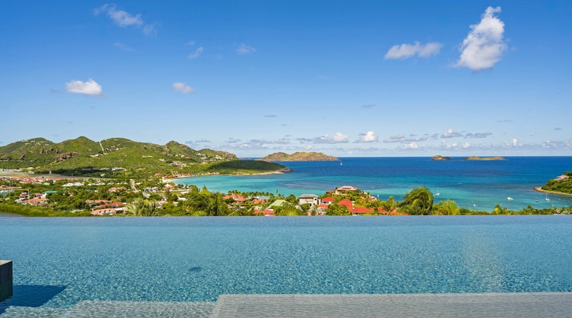Stunning infinity pool overlooking turquoise Caribbean waters and lush tropical coastline creates the perfect paradise backdrop.