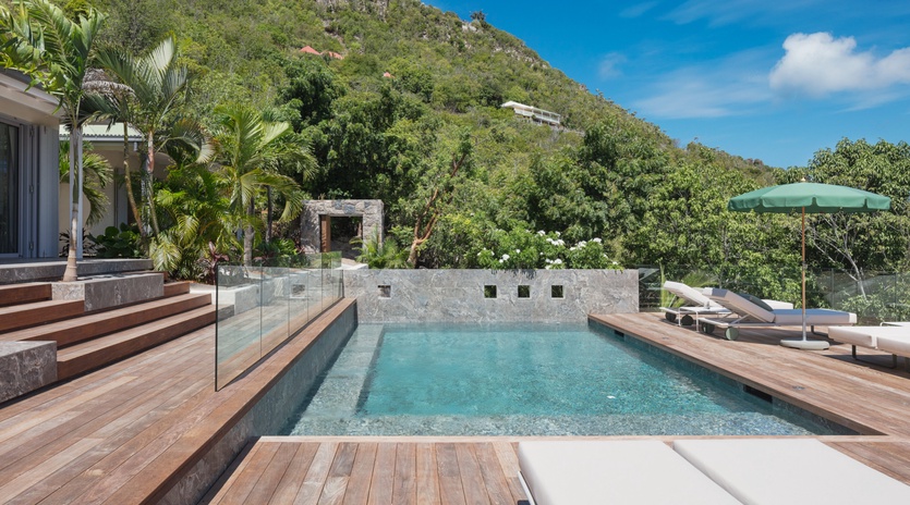 Luxurious infinity pool with tropical mountain backdrop offers serene relaxation surrounded by lush greenery and elegant outdoor lounging spaces.