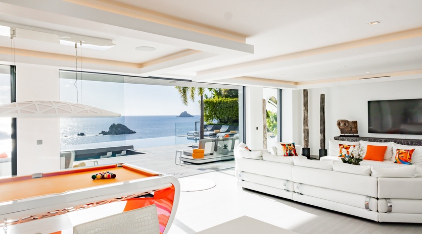 Relax in this stunning oceanfront living space where floor-to-ceiling windows frame breathtaking sea views, while you unwind on plush white sofas.