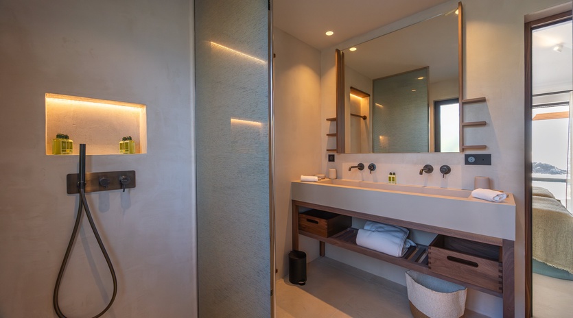 Unwind in your luxurious bathroom featuring a sleek walk-in shower, elegant double vanity with premium amenities, and sophisticated lighting.