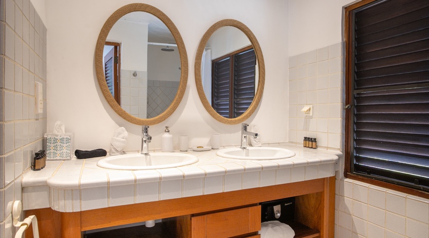 Start your morning refreshed at the dual vanities—elegant oval mirrors, white tile accents, and thoughtful touches like fresh towels and island-style shutters create your serene retreat.