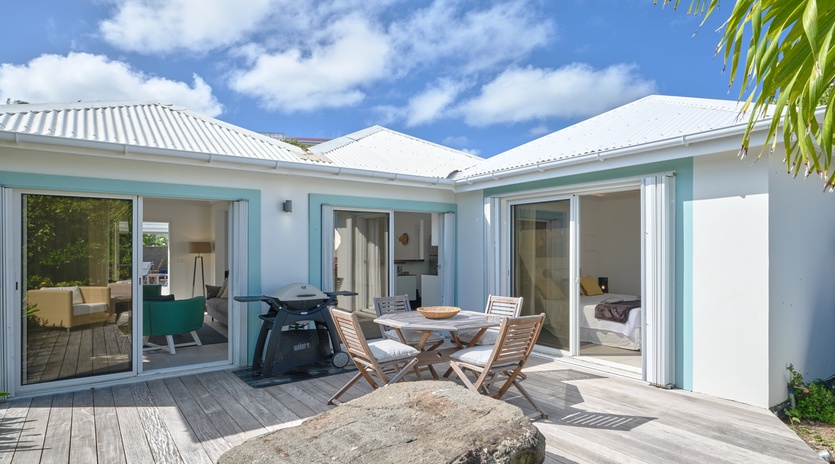 Modern tropical villa with open-plan design featuring turquoise accents and natural stone elements against blue skies.