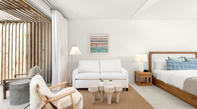 Your elegant retreat features a plush sofa, cozy armchair, and comfortable bed, all bathed in natural light from expansive windows.