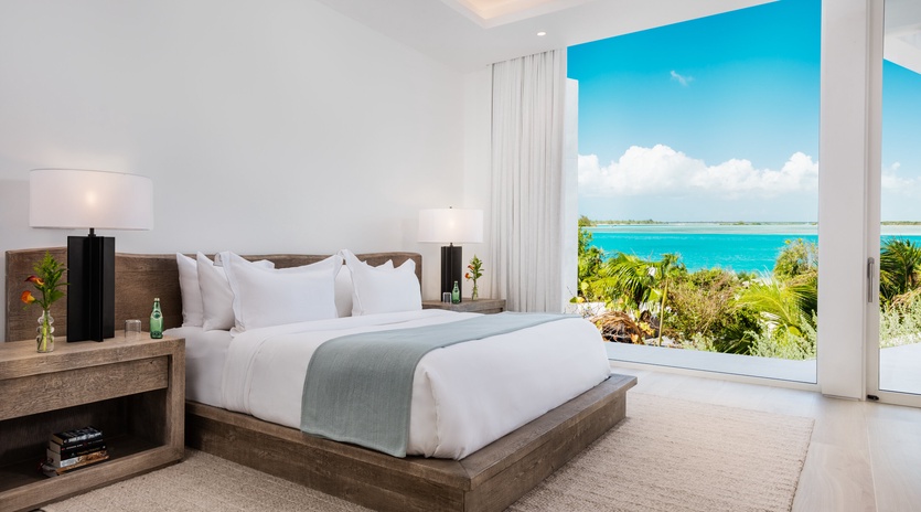 Wake up to crisp white linens and turquoise water views framed by your private balcony. This serene bedroom blends coastal elegance with modern comfort for your perfect island escape.