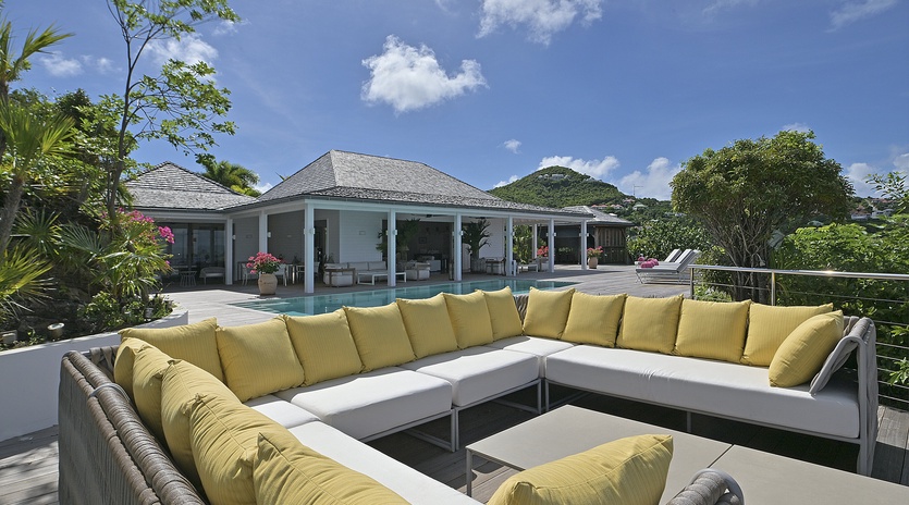 Unwind on your private terrace with stunning tropical views, where vibrant yellow cushions invite relaxation overlooking the sparkling pool.