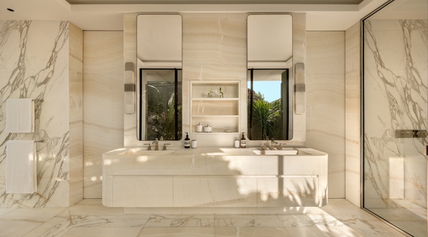 Indulge in your private marble sanctuary with dual vanities and natural light streaming through the window.