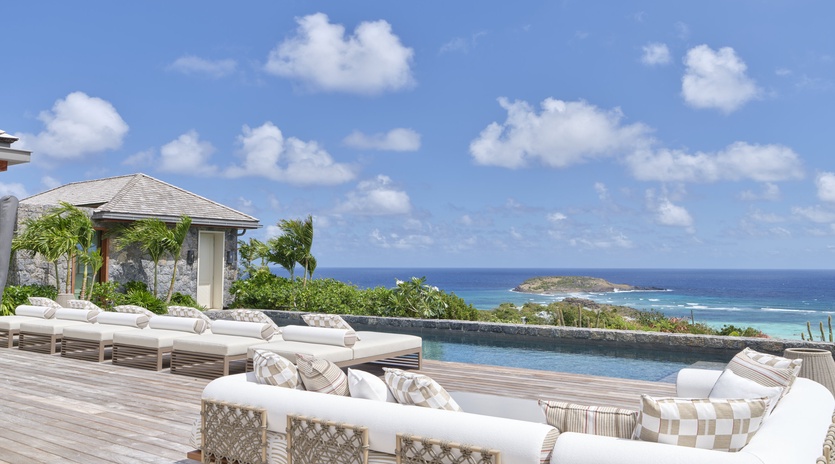 Luxury oceanfront pool deck featuring elegant loungers and stunning sea views across tropical Caribbean waters.