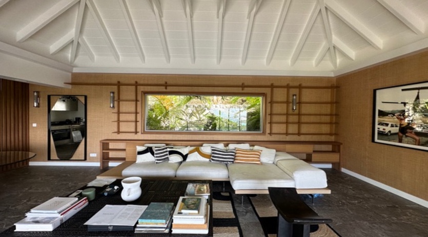 Unwind in your sophisticated living space with exposed beam ceilings, plush seating, and tropical garden views through the picture window.