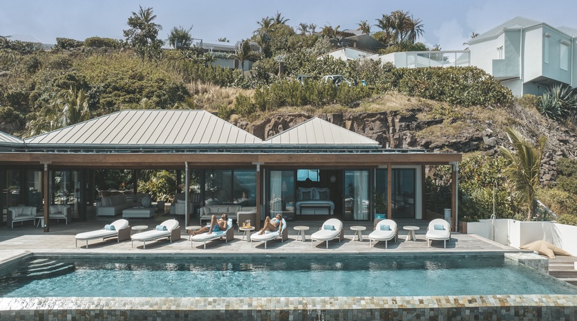 Modern villa with pristine pool surrounded by lush tropical landscape and contemporary architecture.