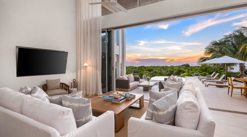 Sink into plush white sofas as gentle breezes flow through your open-air living space, where sunset views paint the sky beyond your private terrace.