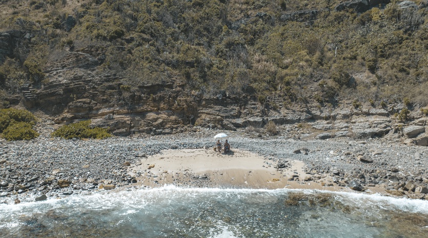 Secluded pebble beach nestled beneath dramatic cliffs, offering crystal-clear waters and peaceful natural surroundings away from crowds.
