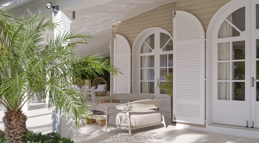 Step onto your private terrace where elegant lounge chairs await beneath graceful arched doors and swaying palm shadows.