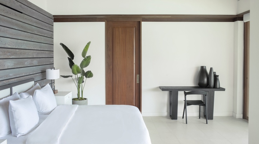 Unwind in your serene bedroom featuring crisp white linens, modern wood accents, and a workspace perfect for quiet moments.
