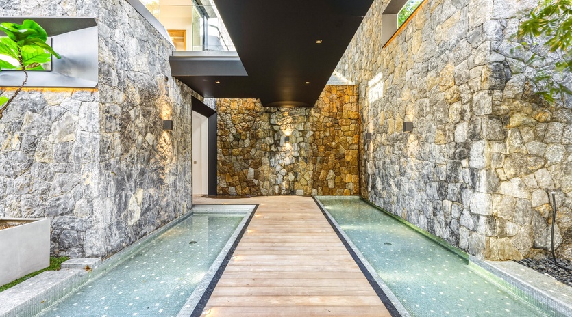 Walk across stunning wooden planks over crystal-clear water, surrounded by dramatic stone walls that create your private sanctuary.