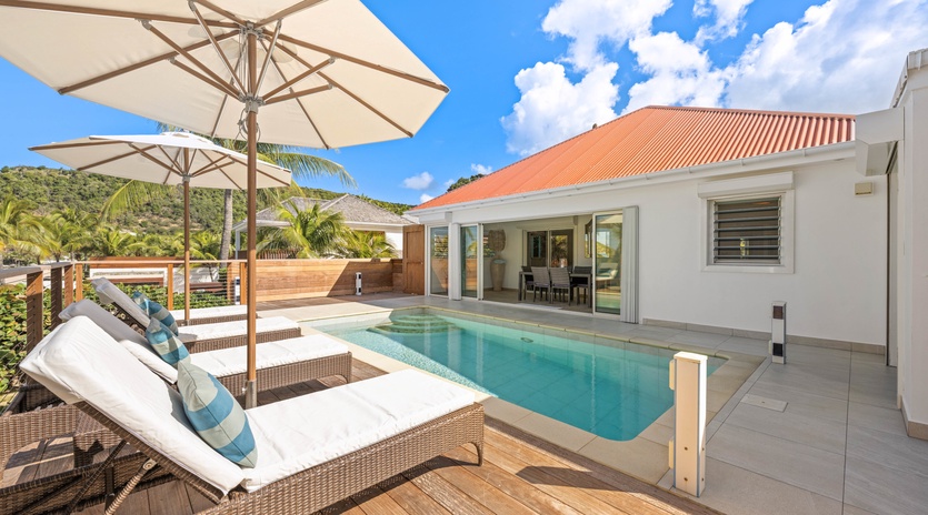Relax on plush loungers beside your private pool, shaded by umbrellas with tropical palms swaying overhead.