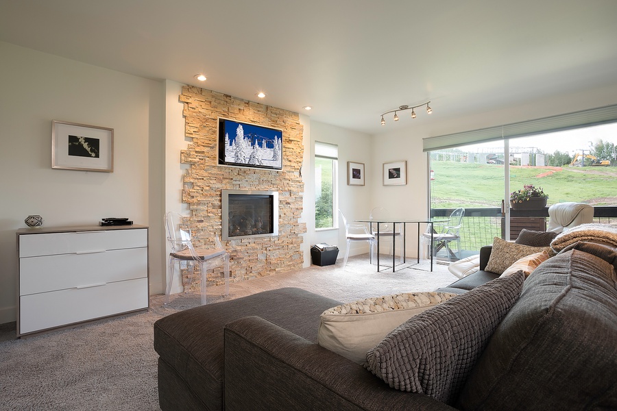 Unwind in your spacious living room featuring a cozy stone fireplace, large windows framing the golf course, and plush seating perfect for relaxing evenings.