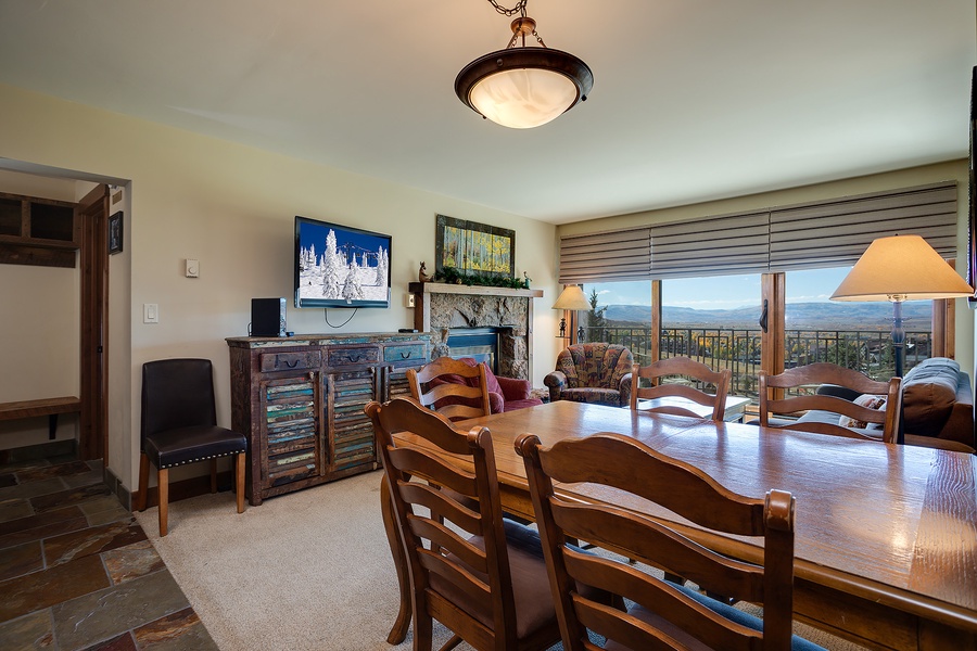 Gather around the rustic wooden table with mountain vistas stretching beyond your balcony. Cozy seating, a warm fireplace, and a TV create the perfect retreat after your adventures.
