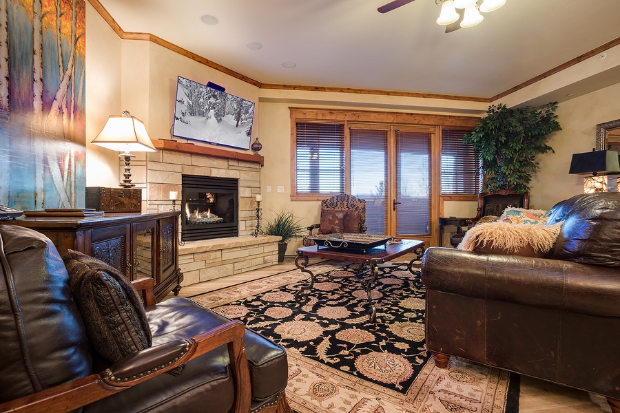 Sink into plush leather sofas by your crackling fireplace, where warm wood tones and mountain artwork create the perfect retreat after a day exploring.