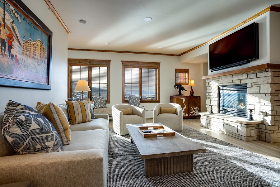 Sink into plush seating by the fireplace, where mountain views frame your mornings and entertainment awaits on the flat-screen TV—your perfect retreat for relaxing together.